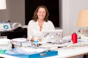 A woman sitting at her desk with papers and a laptop.