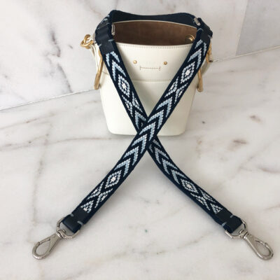 A white purse with two black and white straps