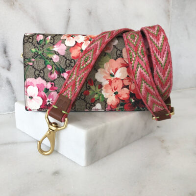 A wallet with a floral print and a pink strap.