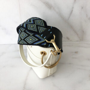 A white purse with a blue and black hat on top of it.