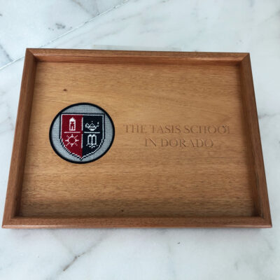 A wooden tray with the seal of the old campus school.
