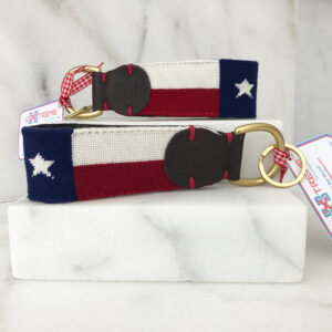 A pair of texas flag key chains sitting on top of a marble counter.