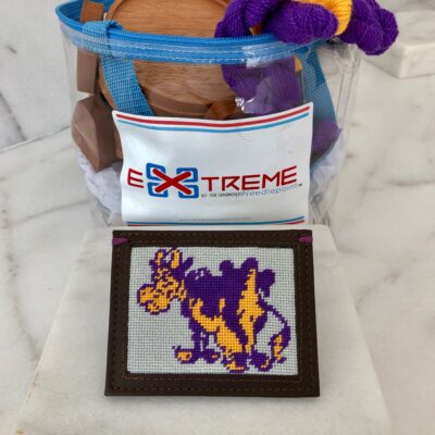 A picture of a purple and yellow cow on the front of a bag.