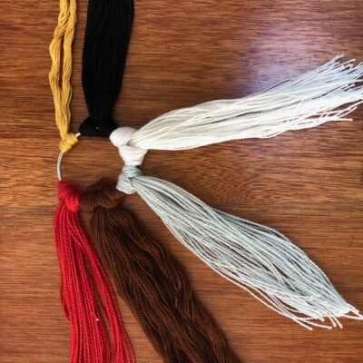 A wooden table with four different colored tassels.