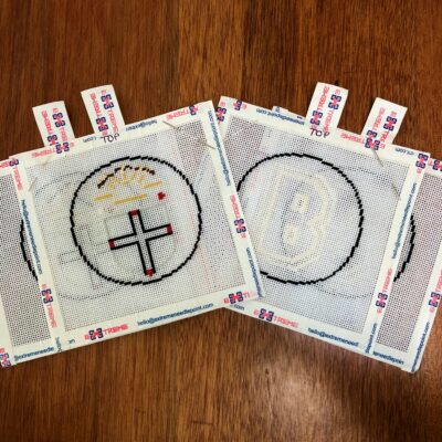 Two coasters with a cross on them sitting on top of a table.