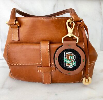 A brown purse with a keychain attached to it.