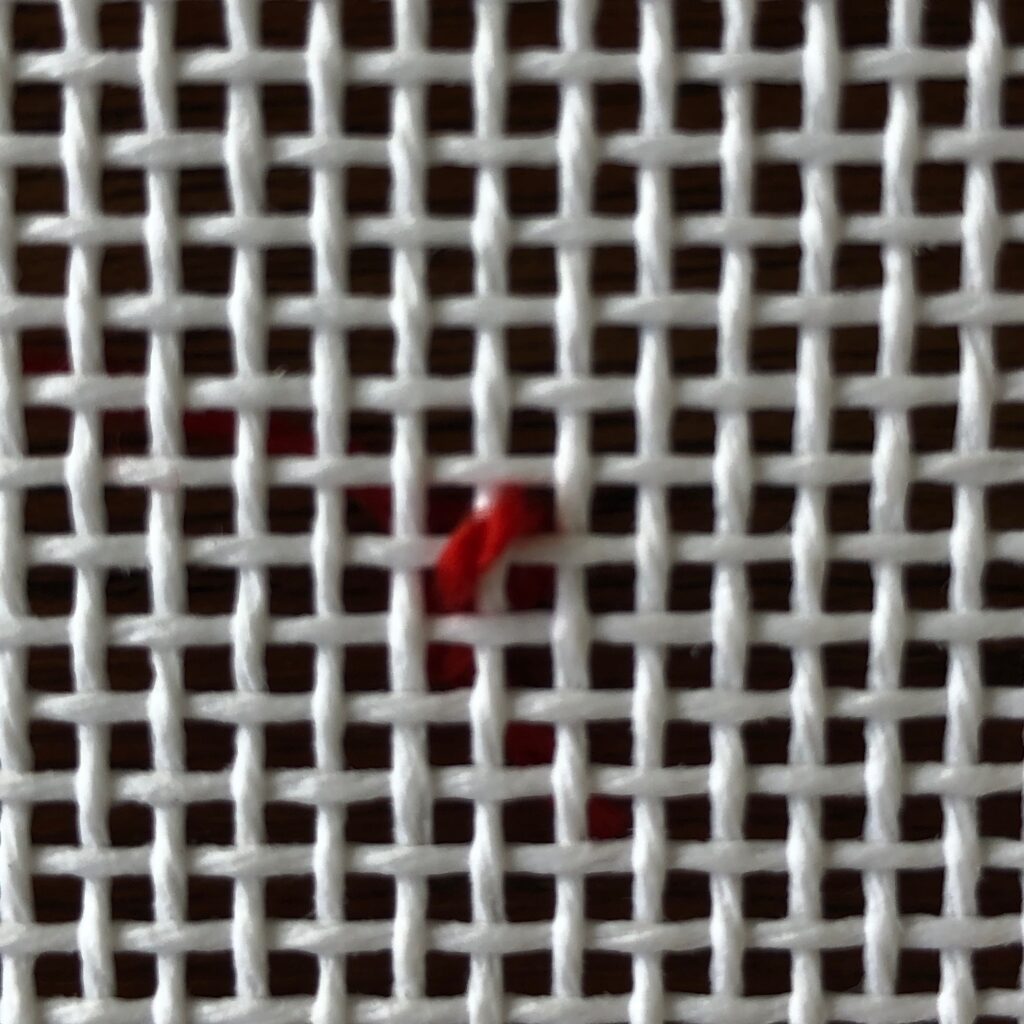 A red pin sitting on top of a metal mesh.